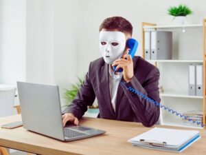 truffatore chiama al telefono con maschera in volto