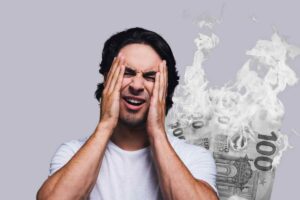 Uomo con mano sul volto e euro in fiamme