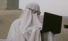 Persona travestita da fantasma con davanti un computer