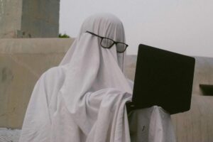 Persona travestita da fantasma con davanti un computer