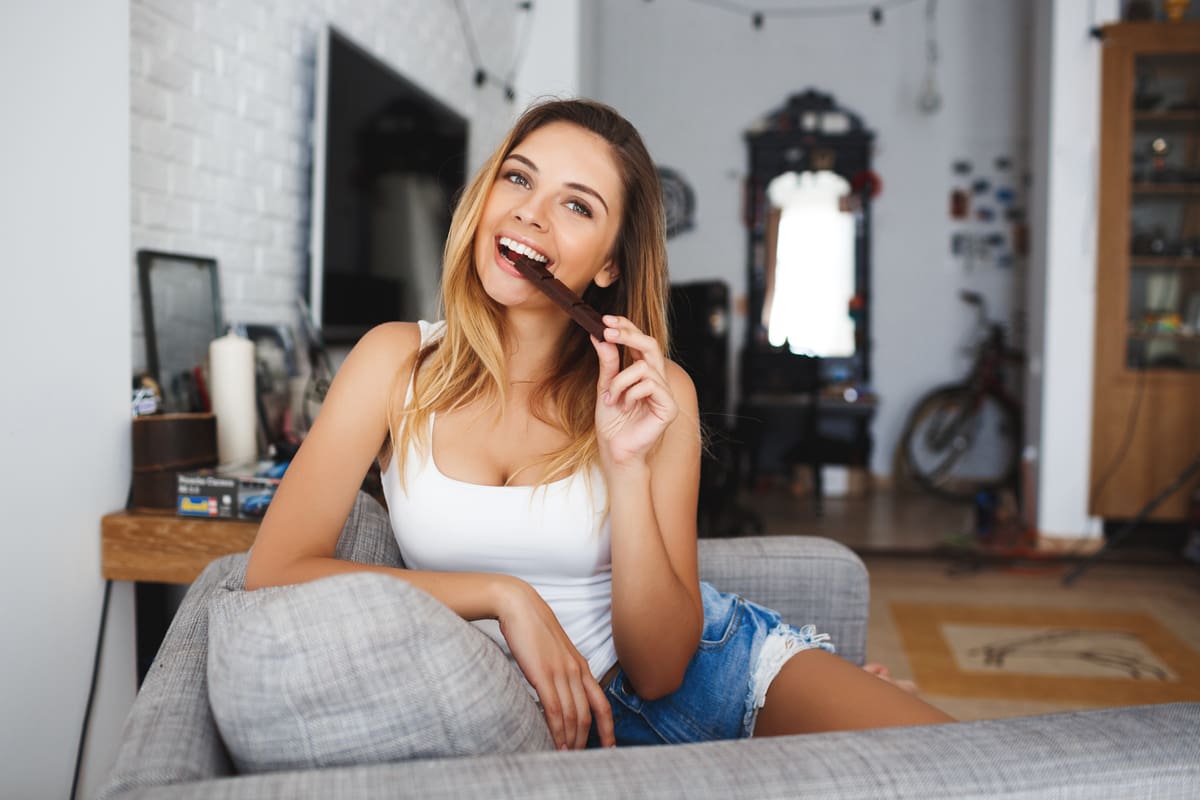Ragazza che addenta una tavoletta di cioccolato