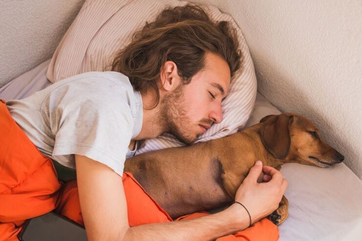 Ragazzo dorme abbracciato al suo cane nel letto
