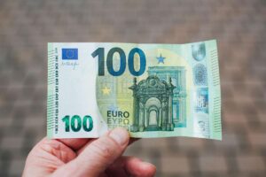 Uomo che tiene in mano una moneta da 100 euro