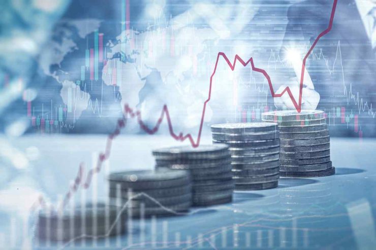 Schermata andamento economia con monete impilate sullo sfondo