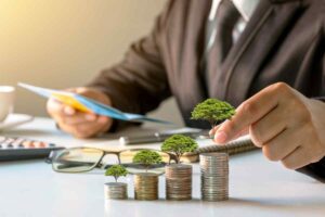 Uomo che impila monete con mini alberi di sopra