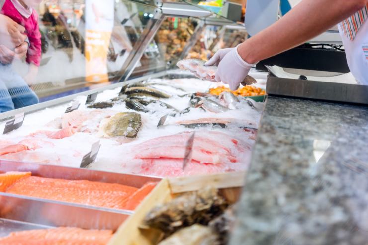 Reparto pesce supermercato. Pescivendolo che serve