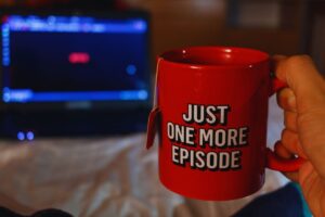 Tazza rossa in primo piano, sullo sfondo uno schermo in cui si intravede il logo netflix