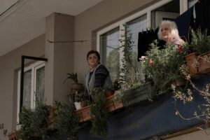 Signore affacciate al balcone che osservano i vicini