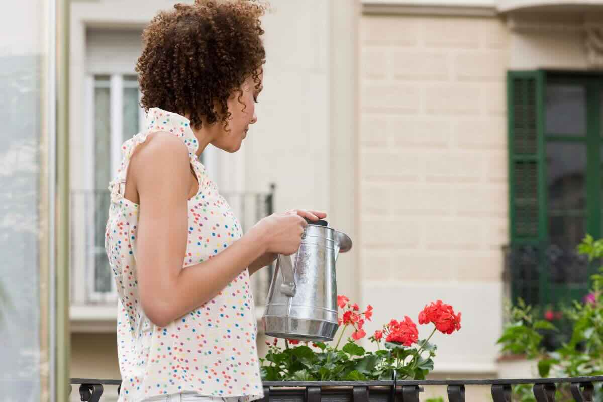 Donna annaffia pianta nel balcone