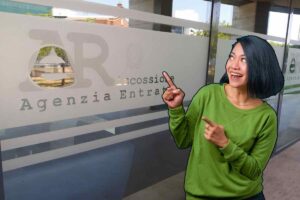 Vetrata ufficio Agenzia delle Entrate e donna sorridente che indica la scritta