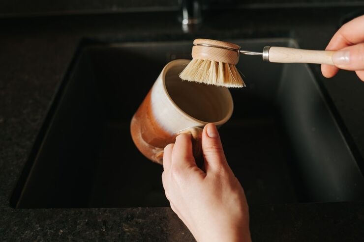 Mano che lava tazza con spazzola