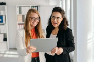 Due donne che sorridono con pc in mano