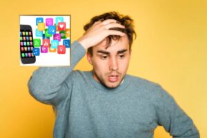 uomo preoccupato con una mano sulla fronte e accanto un cellulare con le App