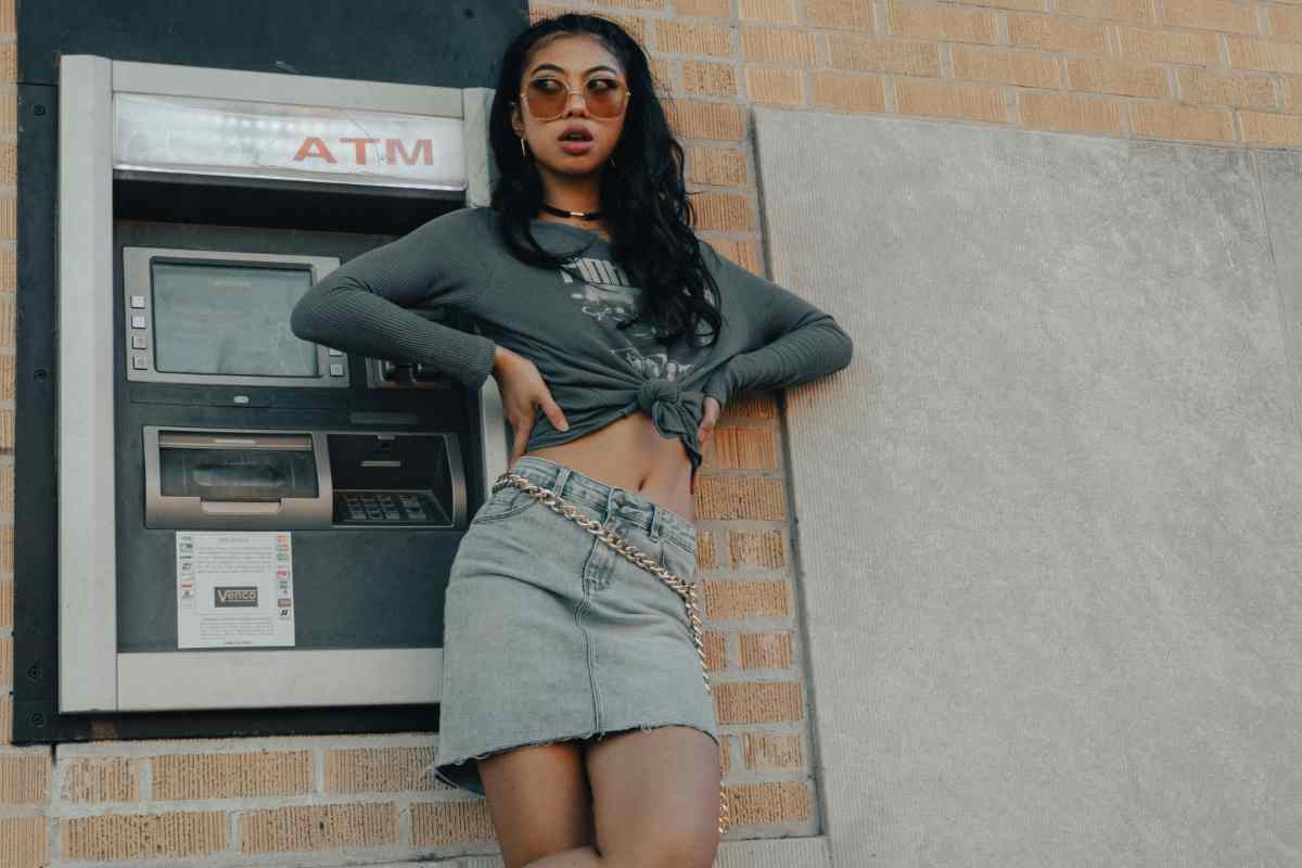 Ragazza in posa davanti a un bancomat