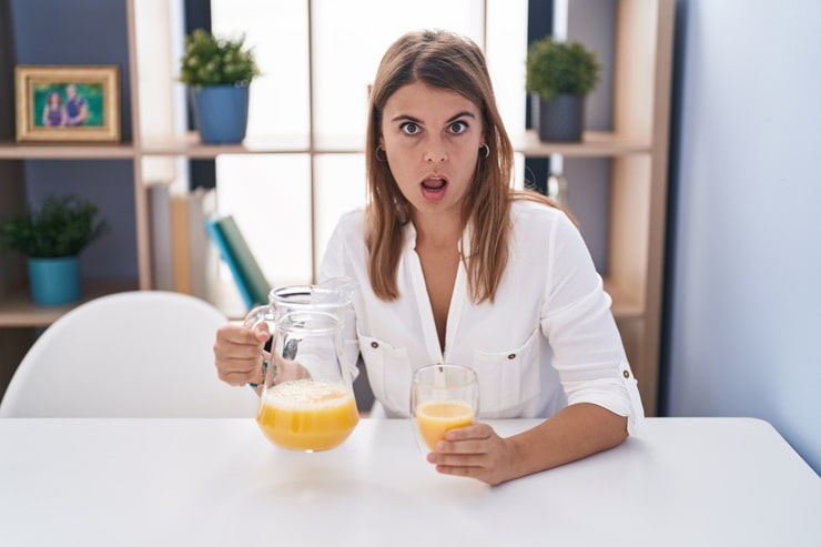 Donna con espressione sorpresa con in mano una caraffa di succo d'arancia