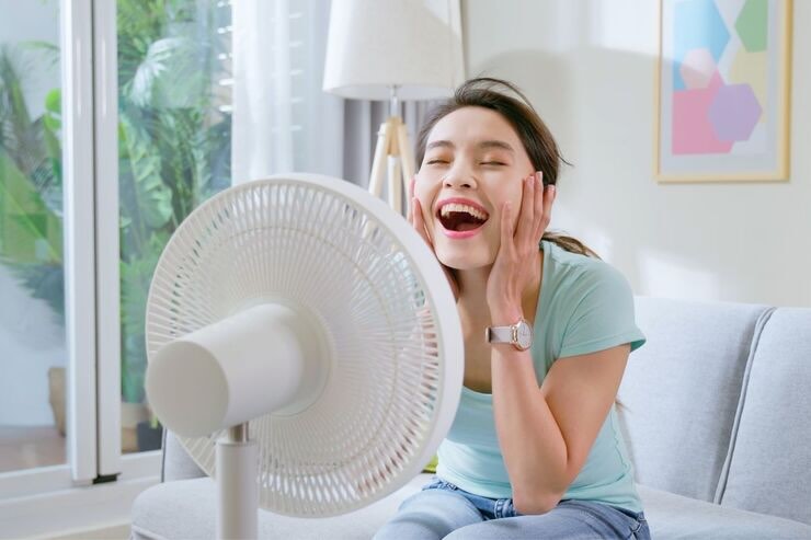 Ragazza sorridente con viso davanti ventilatore