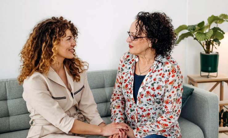 Due donne che si tengono le mani sul divano