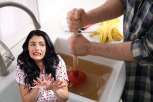 donna disgustata e uomo che stura lavandino