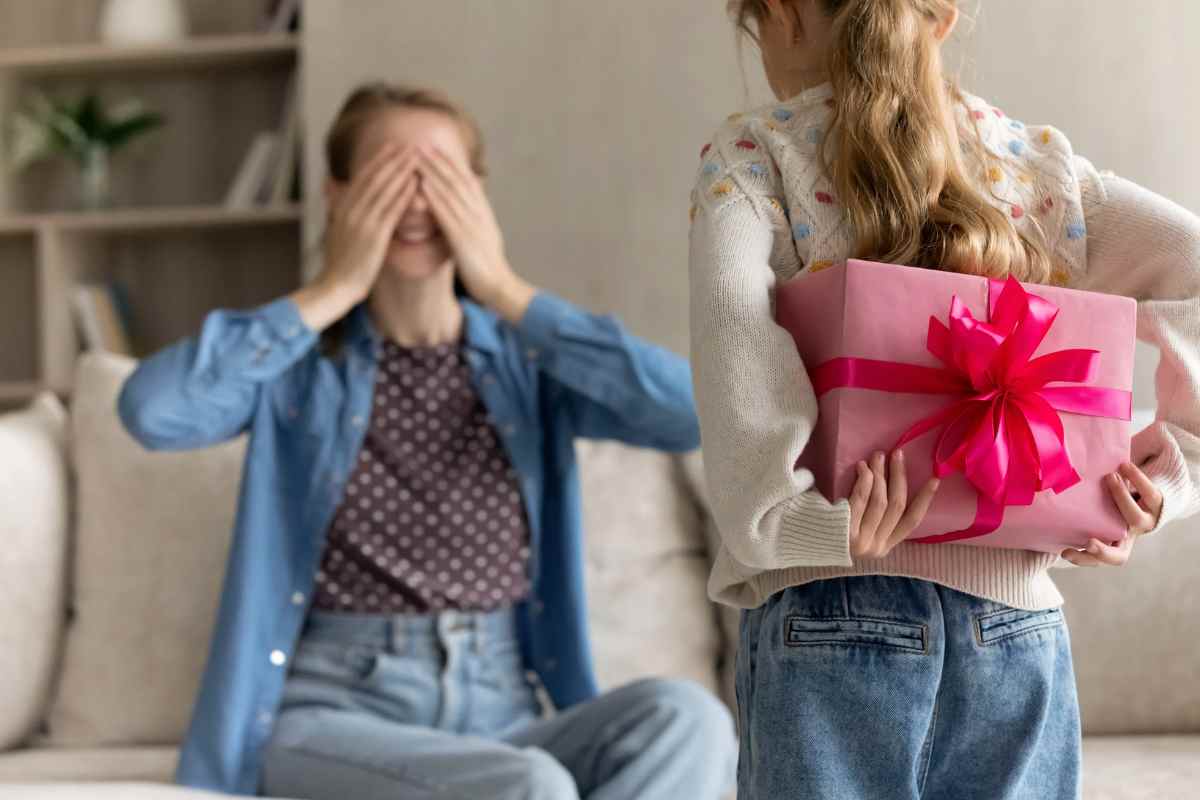 Bambina con regalo e donna con occhi chiusi