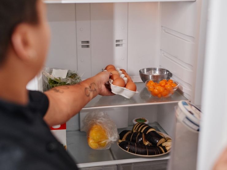 uomo che prende uova dal frigo