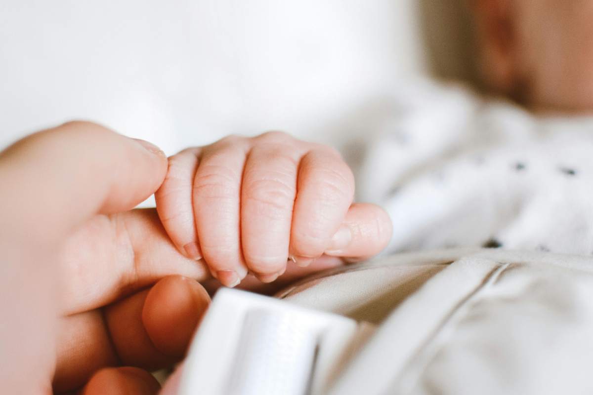 La manina di un neonato che stringe il dito della madre