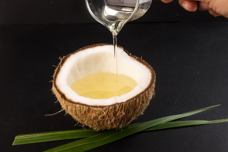 noce di cocco con dentro miele e olio di cocco che cade dall'alto