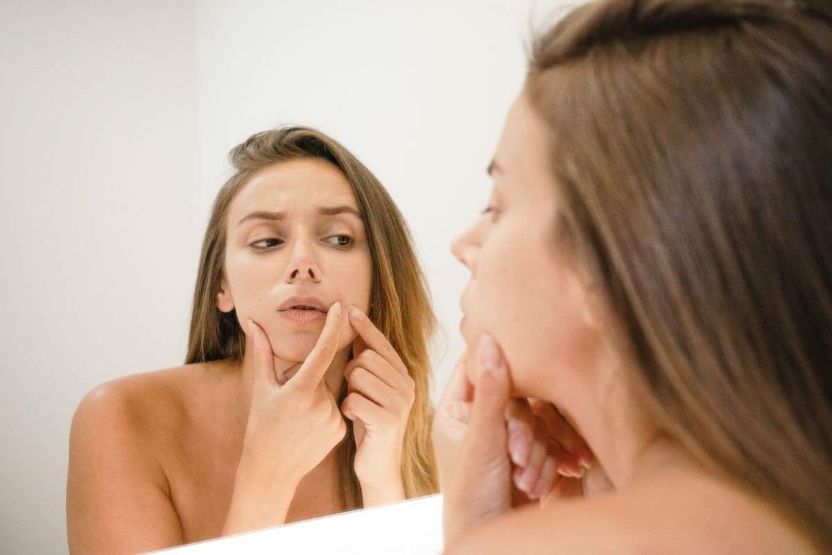 Ragazza allo specchio che si tocca viso