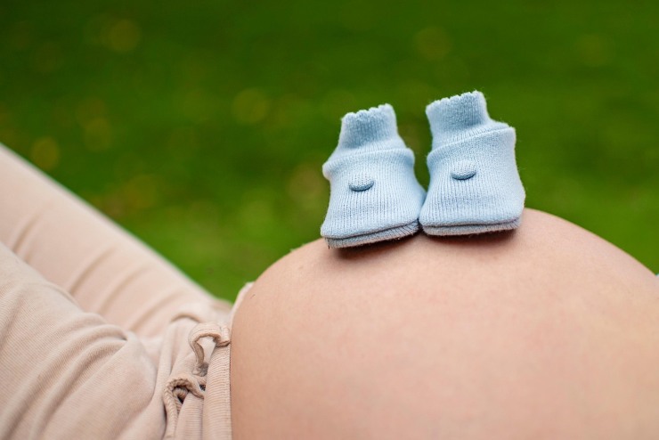 Scarpette da neonato poggiate su grembo donna incinta