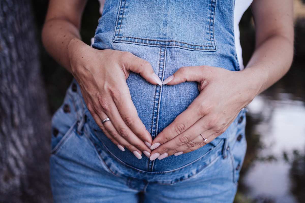 Donna incinta che fa il simbolo del cuore con le mani sul proprio grembo