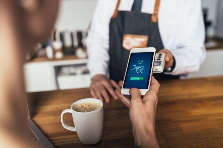 Persona paga con il cellulare il caffè che si trova sul bancone davanti a lui