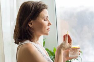 Donna con pasticca e bicchiere d'acqua in mano