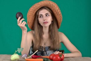 donna con in mano un avocado e davanti a sé degli ortaggi su un tavolo