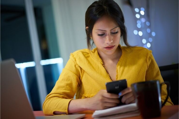 Ragazza con camicia gialla legge qualcosa sullo smartphone