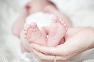 Un neonato inquadrato dal basso: la madre gli tiene i piedini