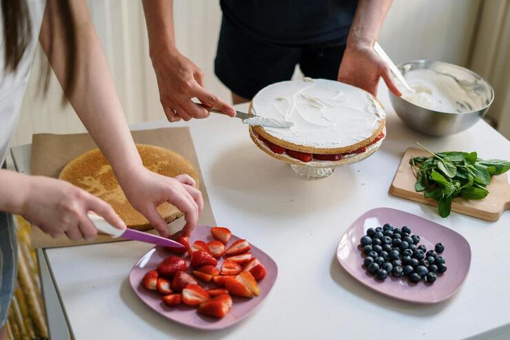 Donne che preparano una torta con fragole e mirtilli