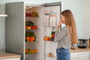 donna che si tappa il naso davanti ad un frigo aperto