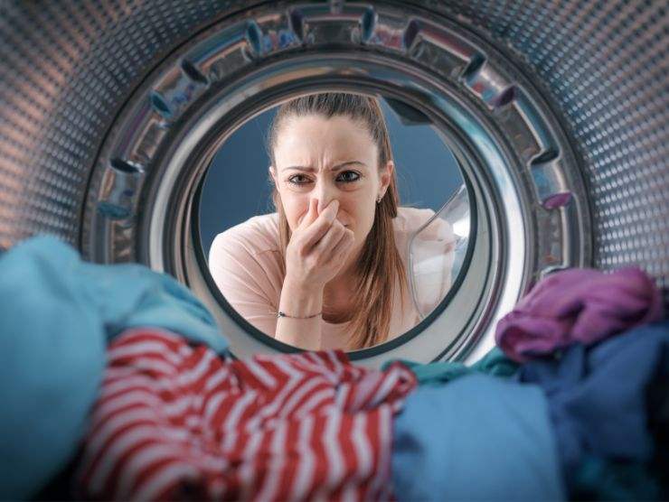 donna che si tappa il naso per i cattivi odori che provengono dalla lavatrice