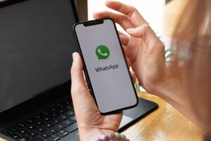 Mani di persona con smartphone e logo whatsapp sullo schermo