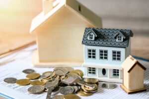 casa in miniatura con soldi e chiavi