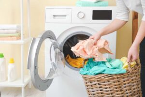 braccia che mettono indumenti colorati in lavatrice