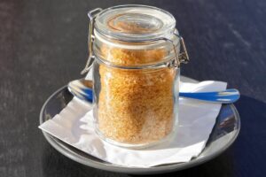 Barattolino di zucchero di canna con cucchiaino accanto