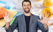 uomo con mani aperte e prodotti pulizie sullo sfondo