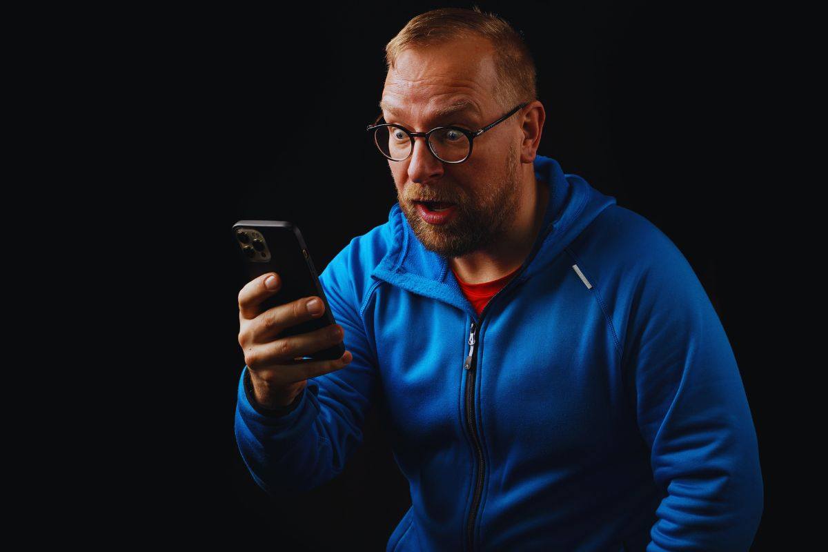 Uomo sconvolto con smartphone in mano