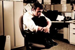 Uomo accovacciato sulla sedia dell'ufficio