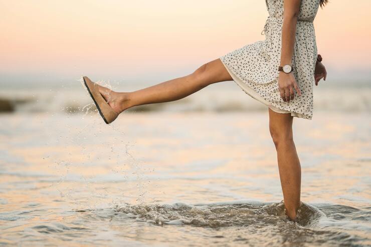 Ragazza in abito corto che mette i piedi in acqua