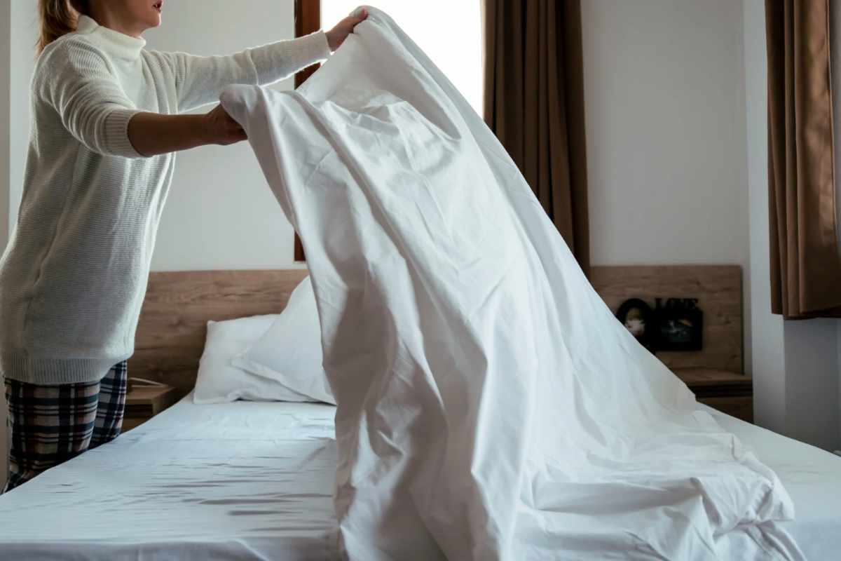 Donna che toglie le lenzuola dal letto