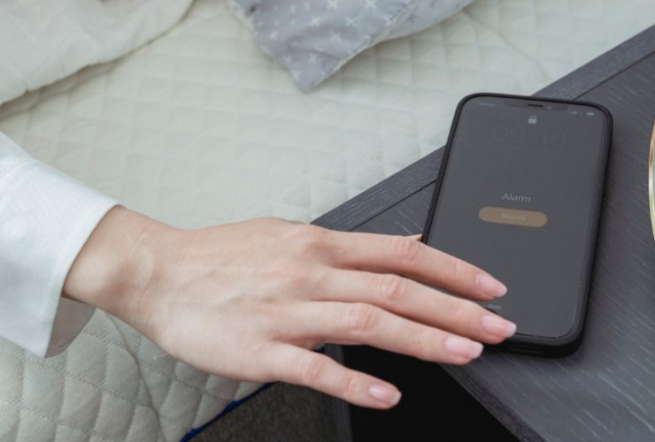 donna a letto che poggia lo smartphone sul comodino