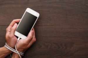 mani legate dal cavo di uno smartphone