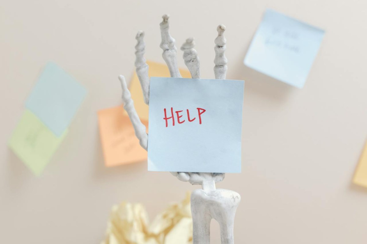 Help scritto su un fogliettino tenuto da una mano scheletrica
