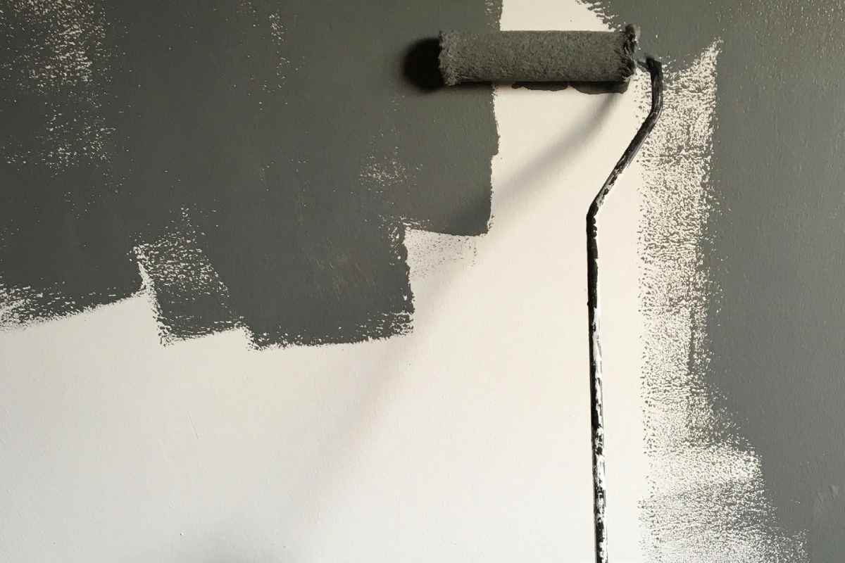 Pennello a rullo che tinteggia di grigio le pareti